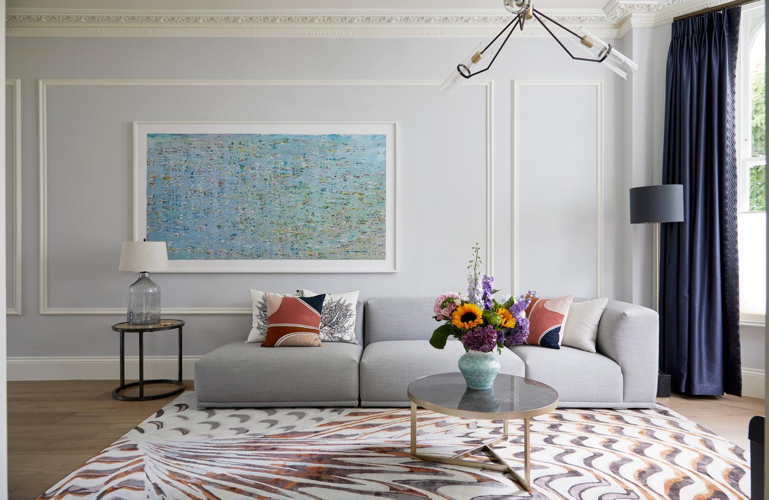 Drawing room in a Kensington townhouse featuring a limited-edition Pheasant rug from The Rug Company inspired by Chihuly's glasswork. The rug's design resembles the wing-like motif of a pheasant, twisting and contorting across the composition. A three-piece modular sofa with clear lines and precise proportions, designed by Andersen & Voll, provides comfortable seating upholstered in textiles from Kvadrat.