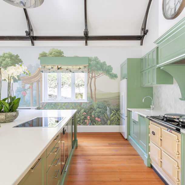 Green kitchen with a cream range cooker, white island and botanical mural, from a Kia Designs interior design project