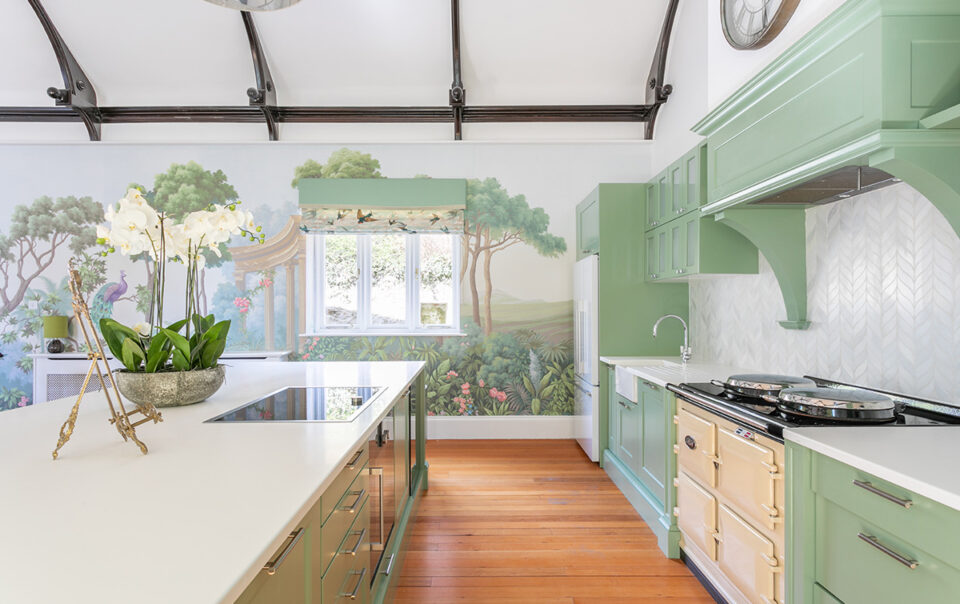 Green kitchen with a cream range cooker, white island and botanical mural, from a Kia Designs interior design project