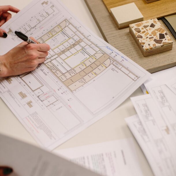 Marking up interior architecture floor plans beside stone, timber and terrazzo samples