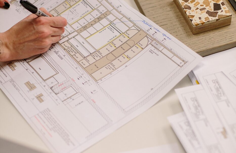 Marking up interior architecture floor plans beside stone, timber and terrazzo samples