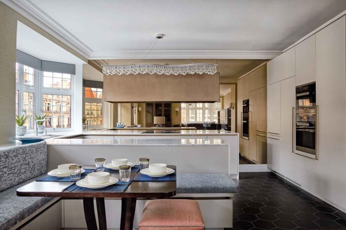 Luxury kitchen with a banquette dining nook, handleless units, black hexagonal floor tiles and a crystal pendant