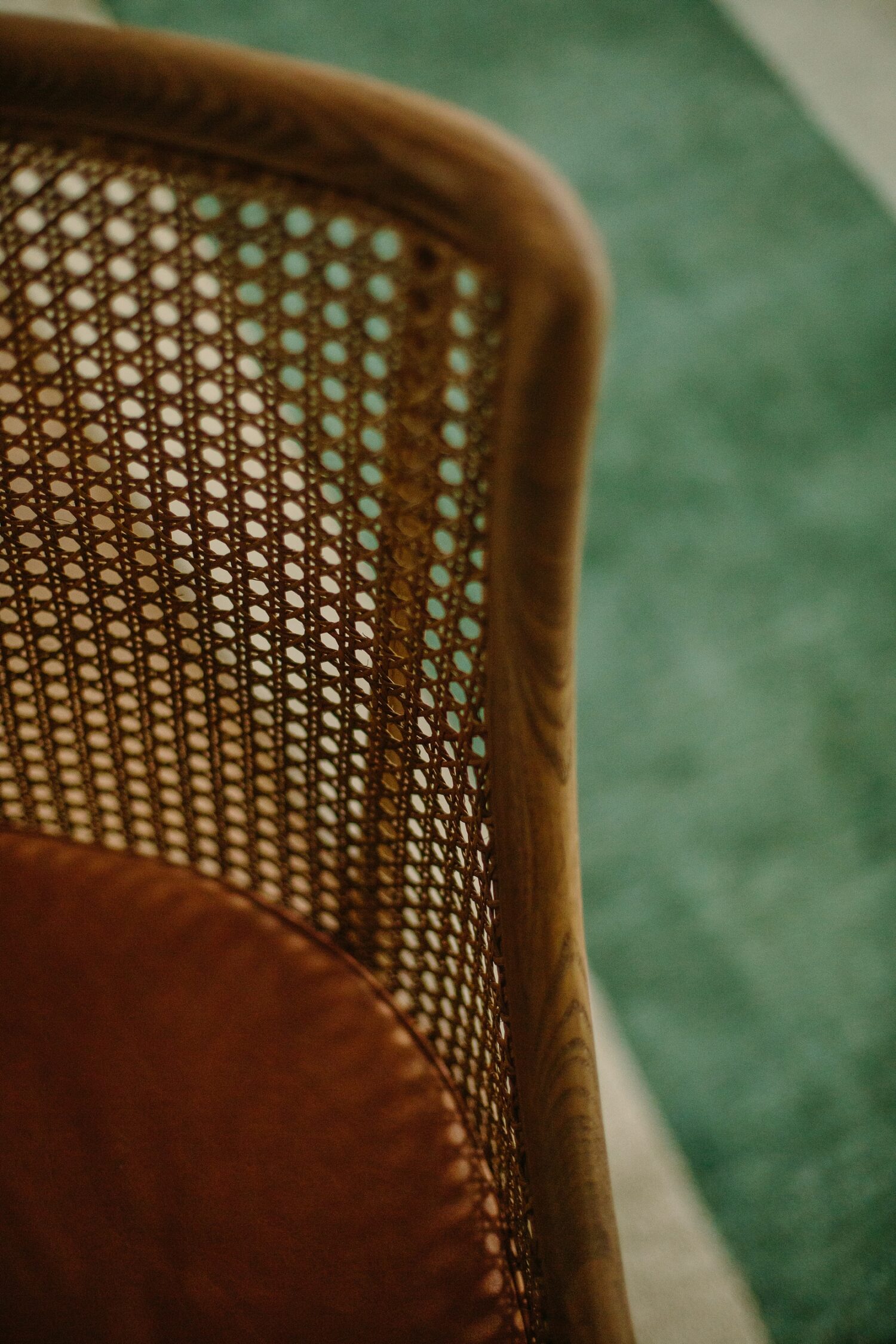 A close up shot of a swivel chair from Oka, crafted in weathered oak with a caramel leather cushion. The double-caned panels not only provide extra strength, but also introduce a unique texture and depth - a tangible reflection of your taste for modern design with a touch of character. 