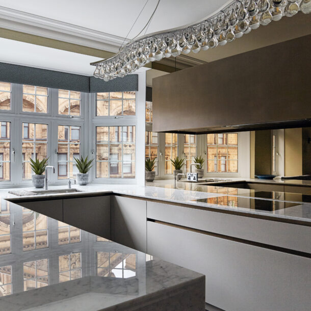 A meticulously designed kitchen in a luxury Knightsbridge apartment, showcasing bespoke elements and refined detailing. The space features hidden storage and smooth, rounded edges in adherence to the client’s preferences. Inspired by London’s grand public establishments and private clubs, the design combines the elegance of boutique hotels with personal touches, creating an atmosphere of understated grandeur. The open-plan layout seamlessly blends the kitchen with dining and lounge areas, embodying a sense of familial conviviality. This stunning space illustrates the principles of how to plan a kitchen with sophistication and functionality.